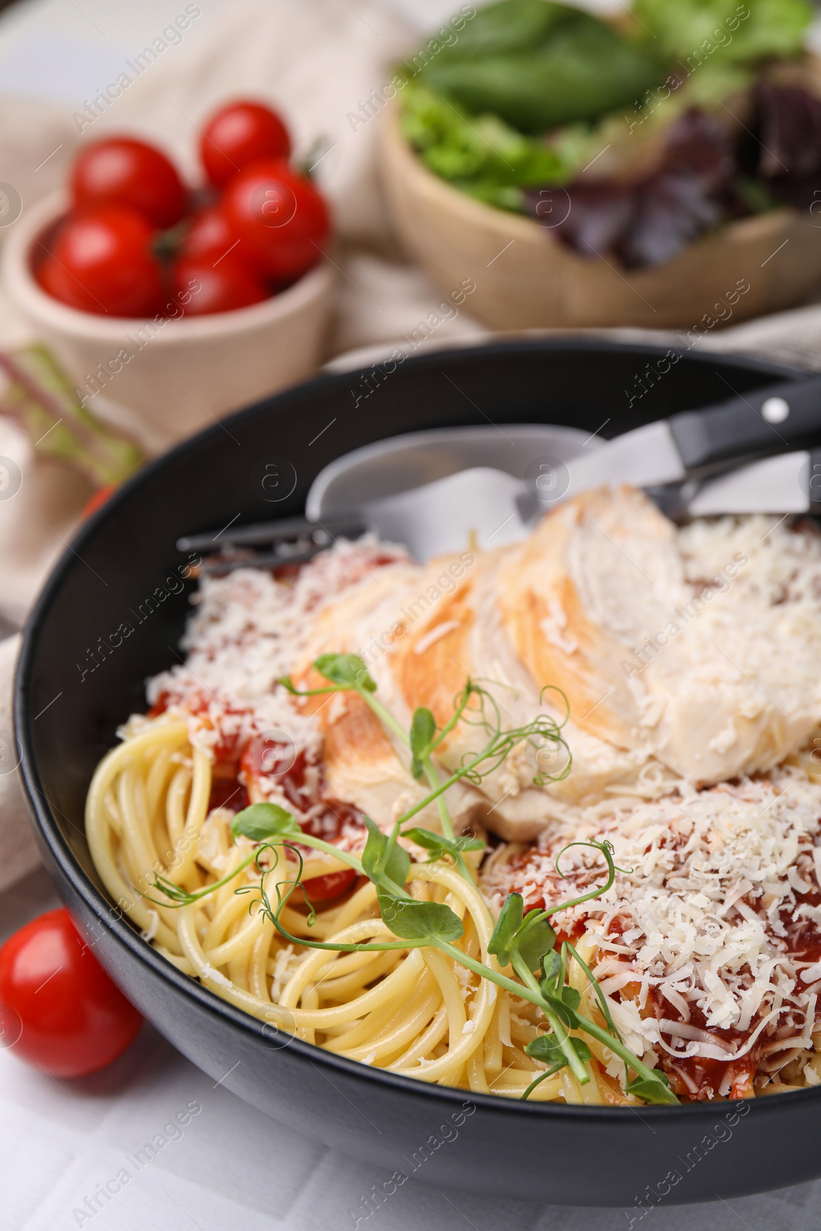 Photo of Delicious pasta with tomato sauce, chicken and parmesan cheese on white tiled table, closeup