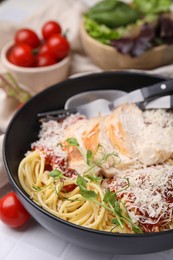 Delicious pasta with tomato sauce, chicken and parmesan cheese on white tiled table, closeup