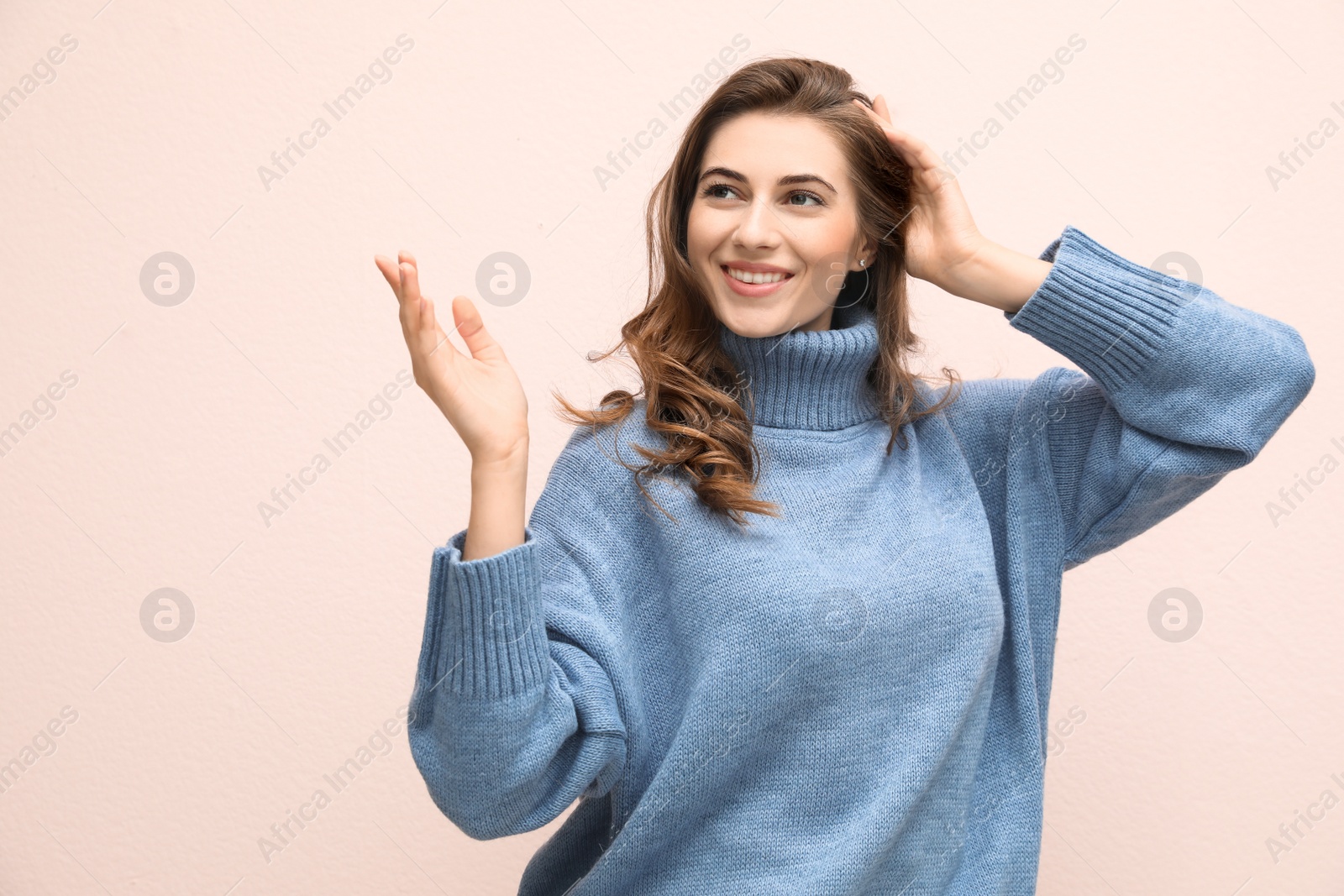 Photo of Beautiful young woman wearing warm blue sweater on light pink background