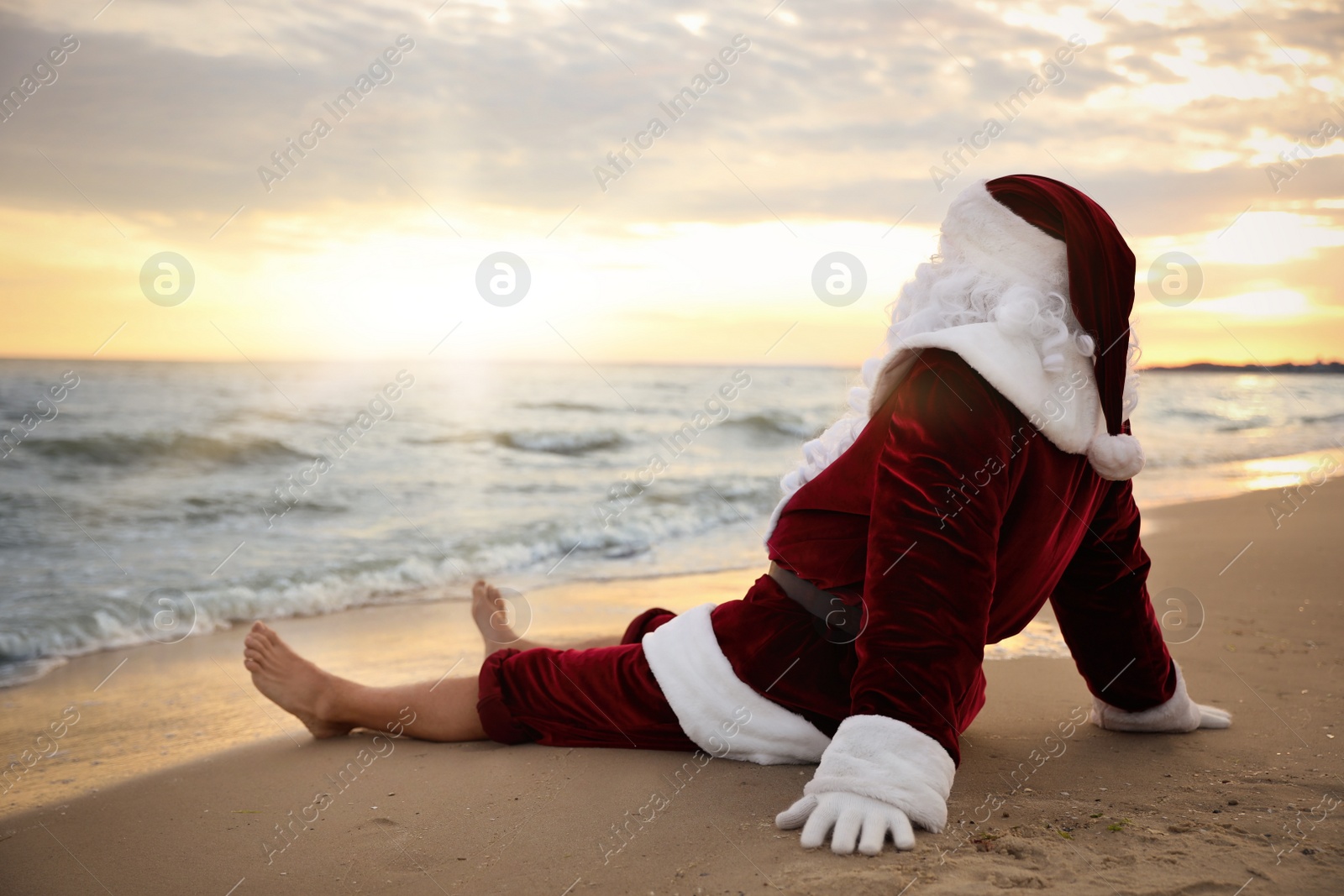 Photo of Santa Claus relaxing on beach, space for text. Christmas vacation