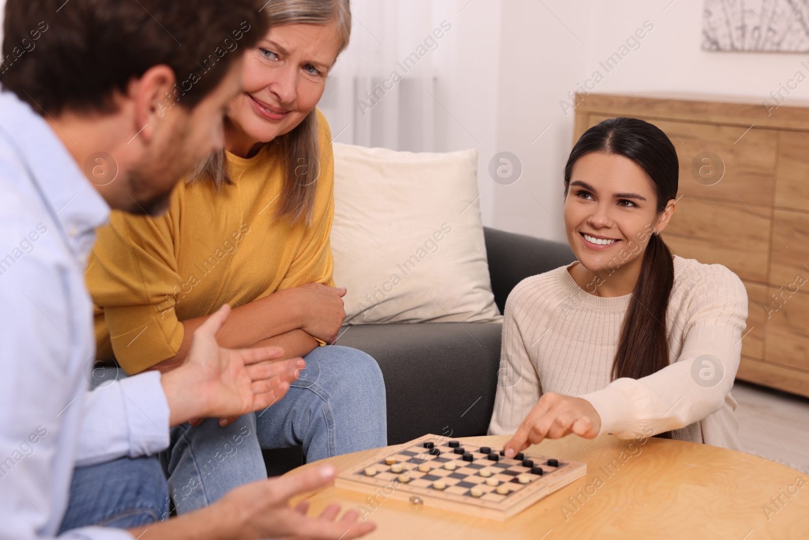 Photo of Family playing checkers at coffee table in room