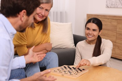 Family playing checkers at coffee table in room