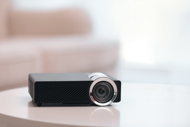 Photo of Modern video projector on white table indoors