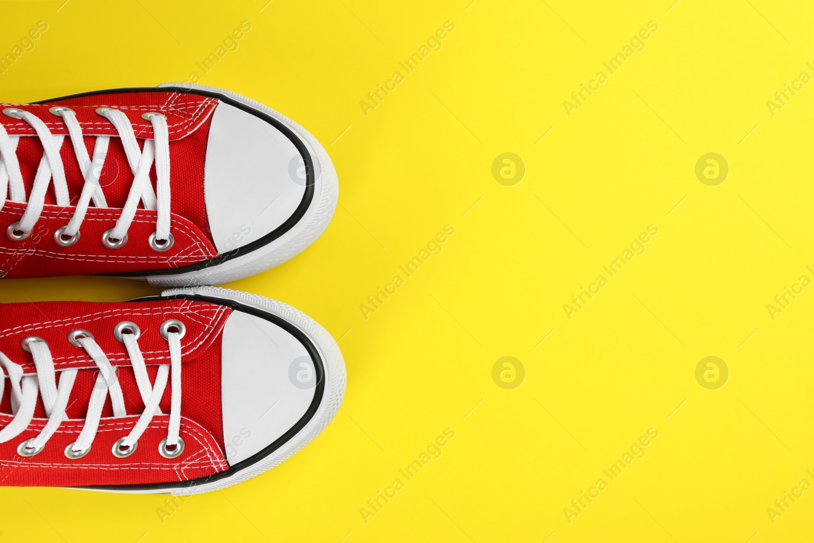 Photo of Pair of trendy sneakers on yellow background, flat lay. Space for text