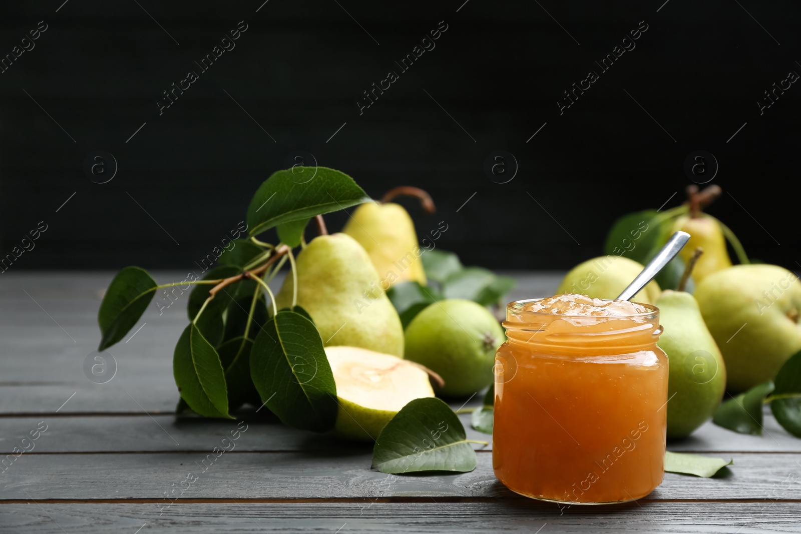 Photo of Delicious pear jam and fresh fruits on grey wooden table