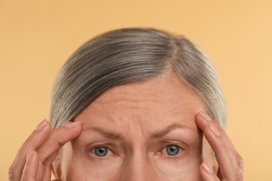 Photo of Woman with wrinkles on her forehead against beige background, macro view