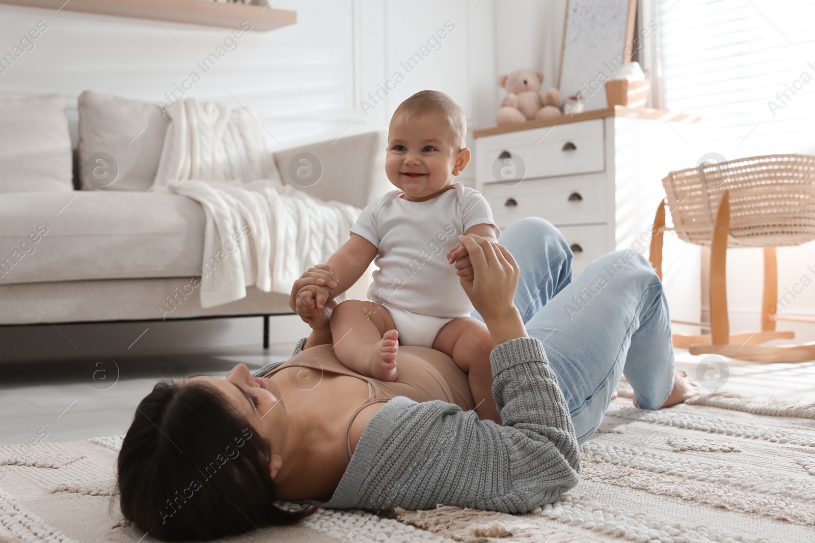 Photo of Happy young mother with her cute baby on floor at home