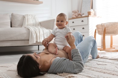 Photo of Happy young mother with her cute baby on floor at home