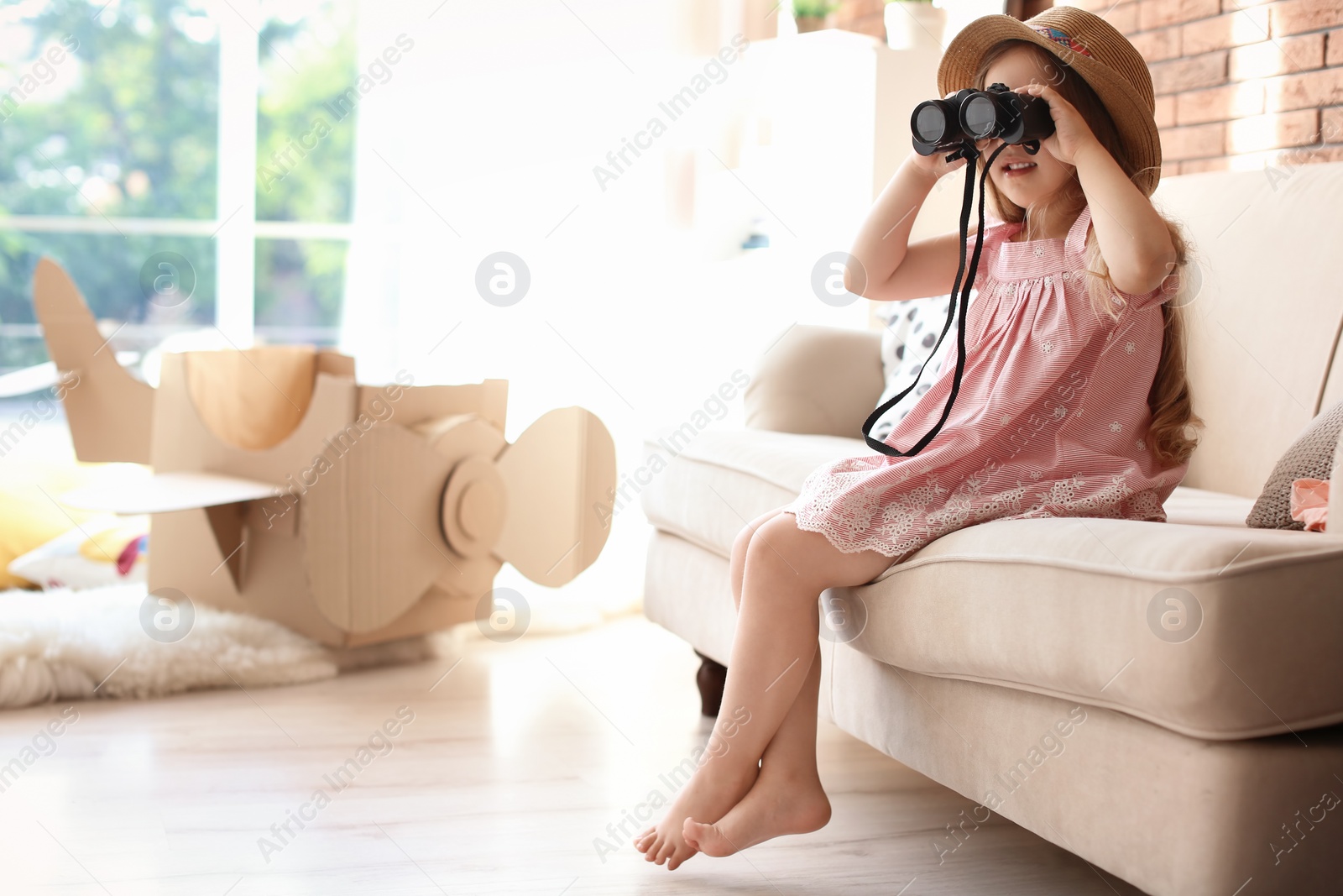 Photo of Adorable little child playing with binoculars at home