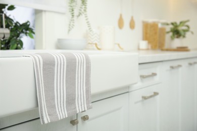 Photo of Clean towel hanging on white sink in kitchen