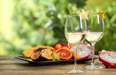 Photo of Delicious exotic fruits and wine on wooden table, space for text