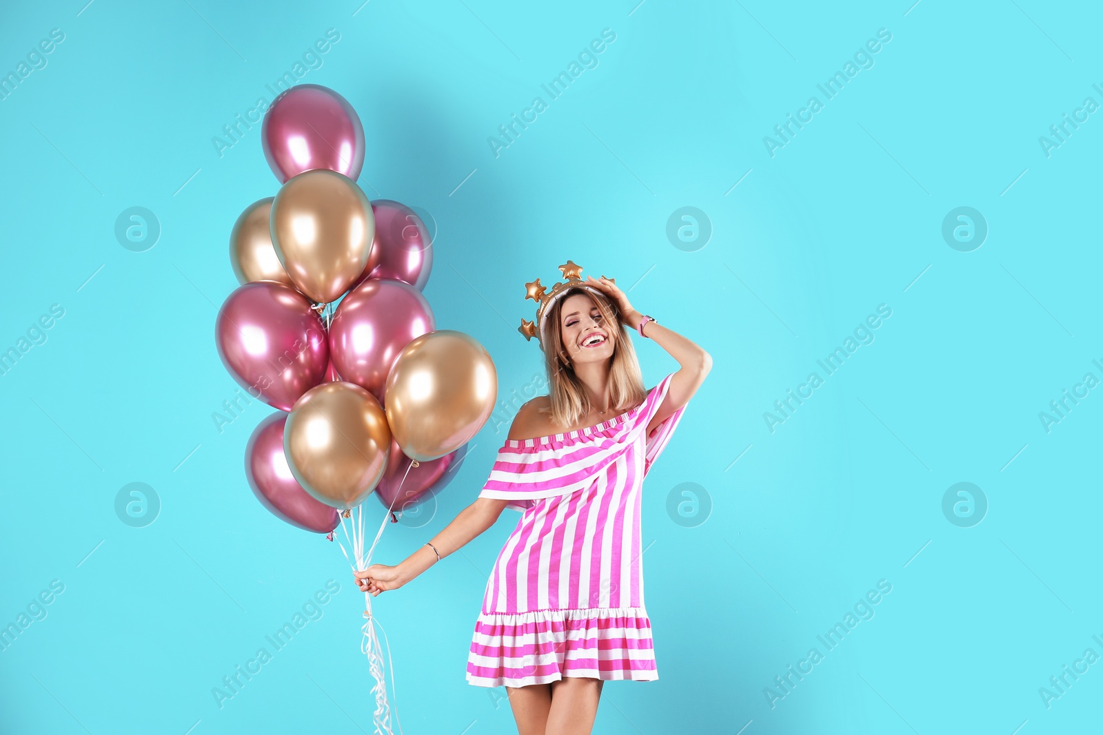 Photo of Young woman with crown and air balloons on color background