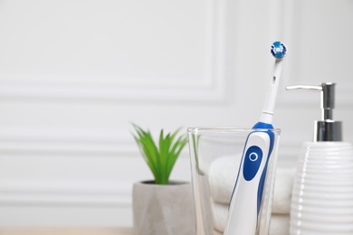 Photo of Electric toothbrush, soap dispenser and towels on blurred background. Space for text