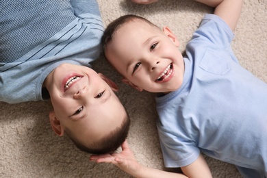 Portrait of cute twin brothers on carpet, top view