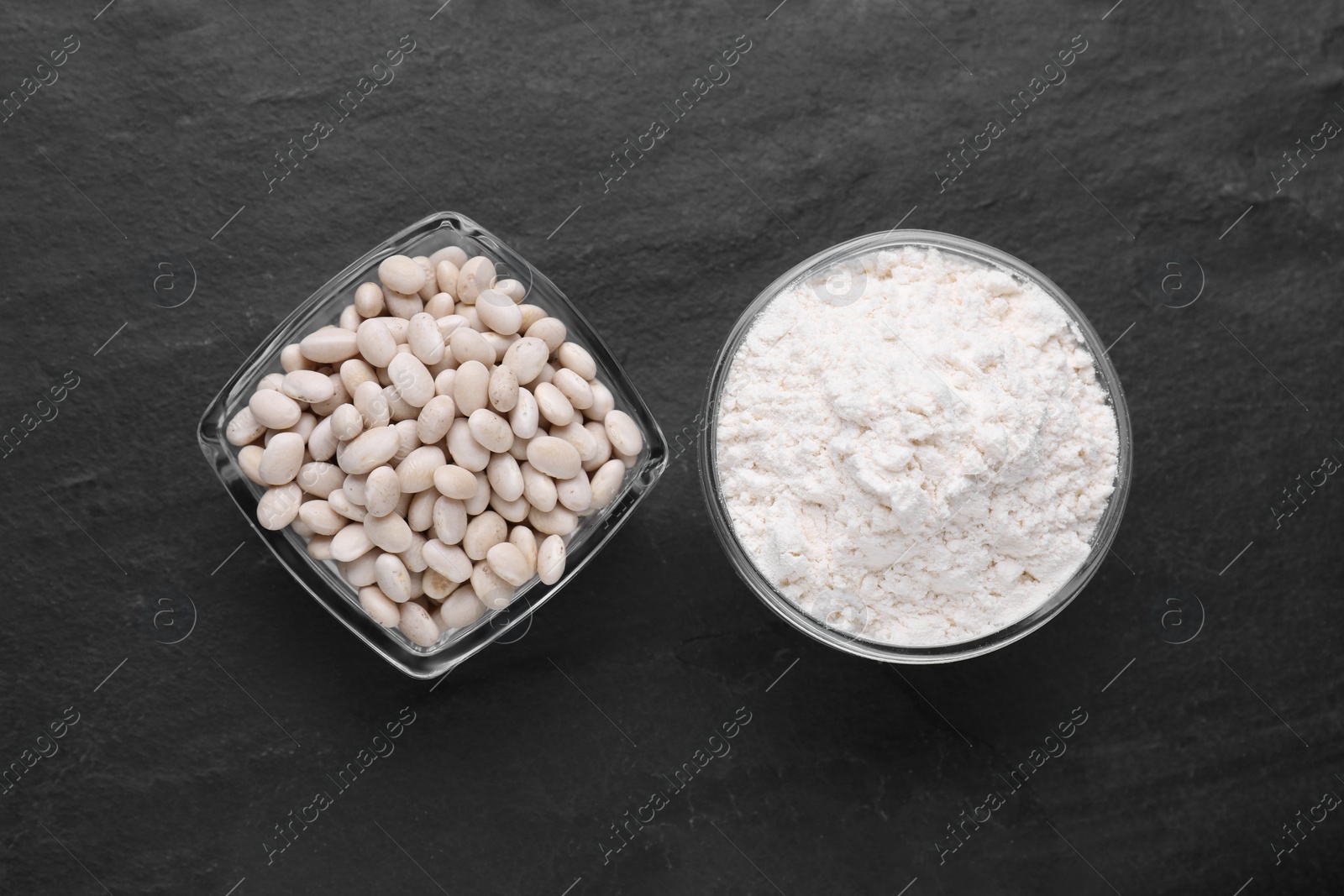 Photo of Bean flour and seeds on black table, flat lay