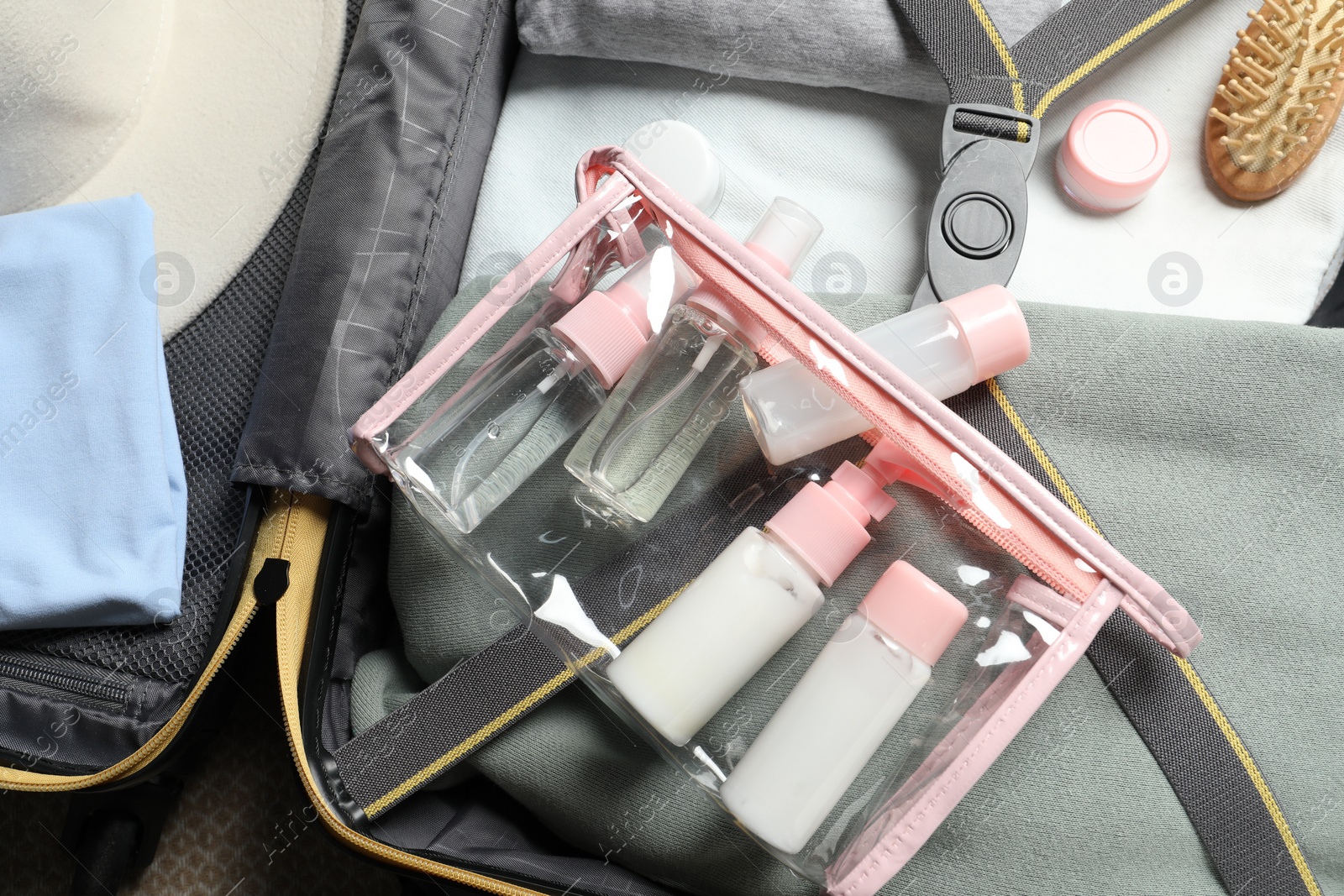 Photo of Plastic bag of cosmetic travel kit in suitcase, top view