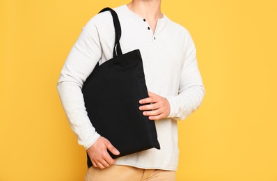 Photo of Young man with eco bag on yellow background, closeup