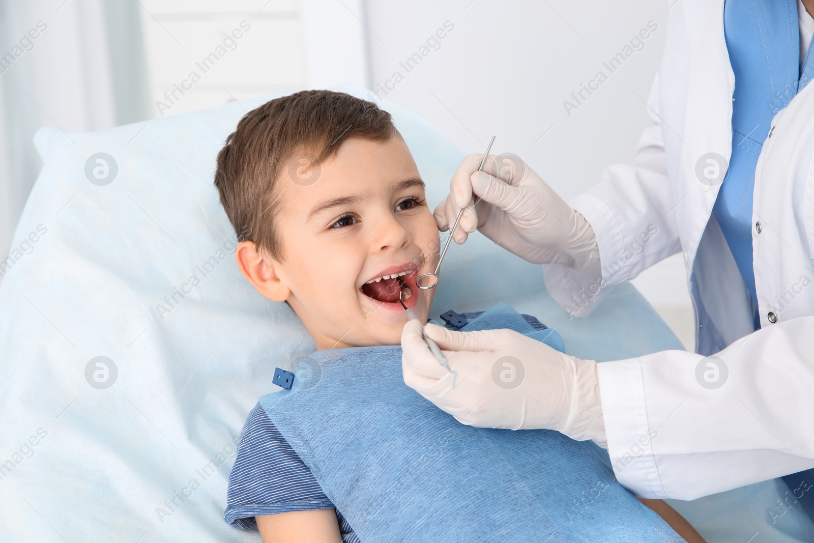 Photo of Dentist examining cute boy's teeth in modern clinic