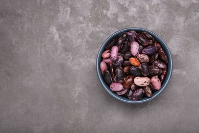 Photo of Bowl with dry kidney beans on grey table, top view. Space for text