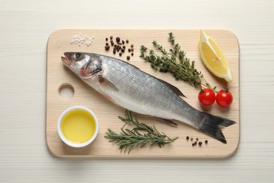 Photo of Tasty sea bass fish and ingredients on wooden table, top view