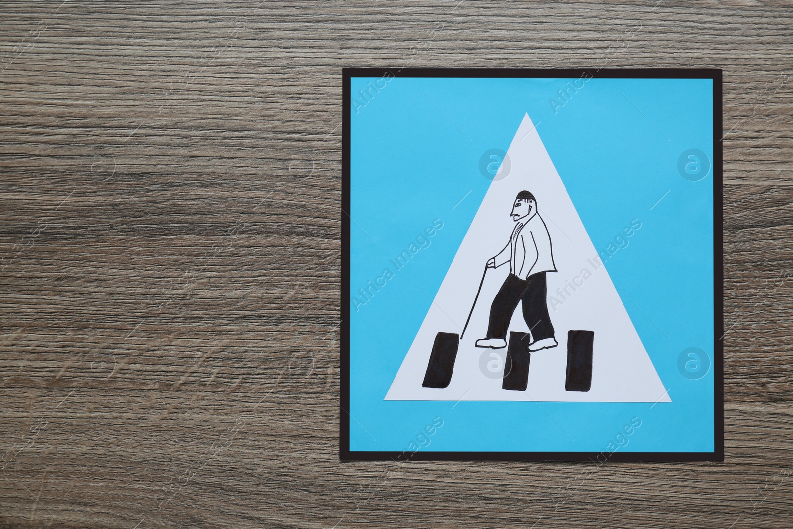 Photo of Pension concept. Paper road sign for pedestrian crossing with elderly man on wooden table, top view and space for text