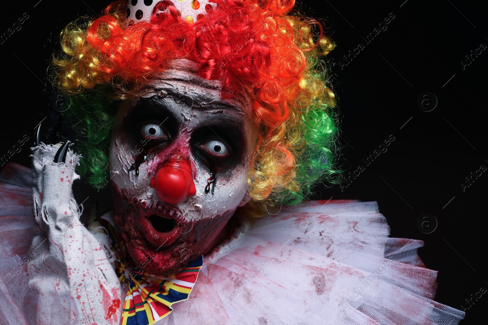 Photo of Terrifying clown on black background. Halloween party costume