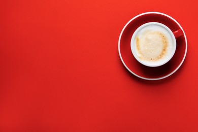 Cup with aromatic cappuccino on red background, top view. Space for text