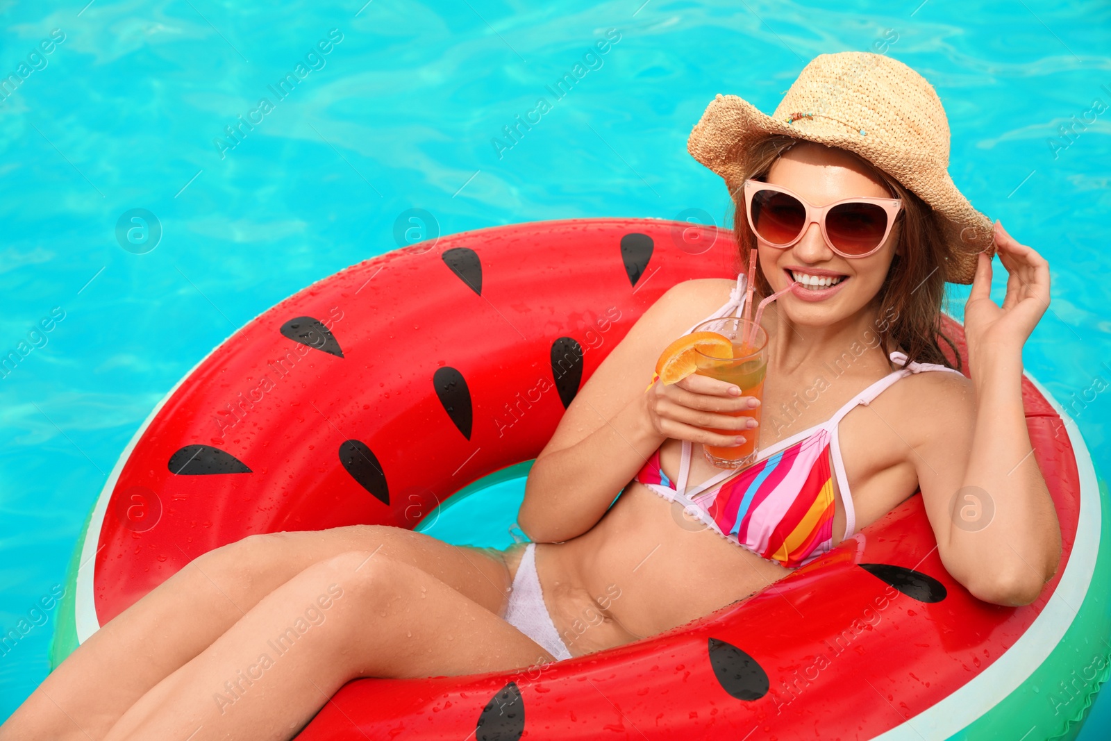 Photo of Young woman with cocktail in pool on sunny day