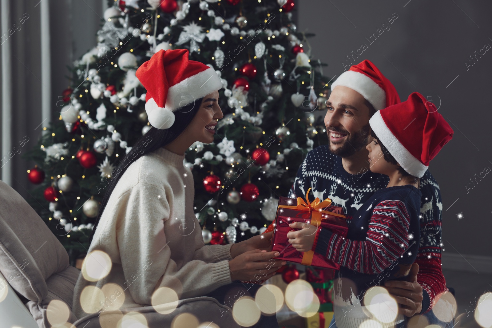 Image of Father with his cute son presenting gift to mother at home. Christmas celebration