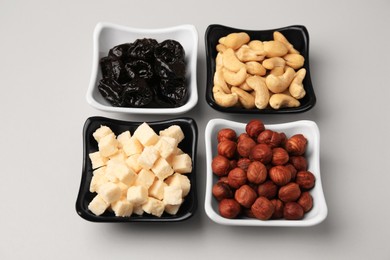 Bowls with dried fruits and nuts on beige background, above view