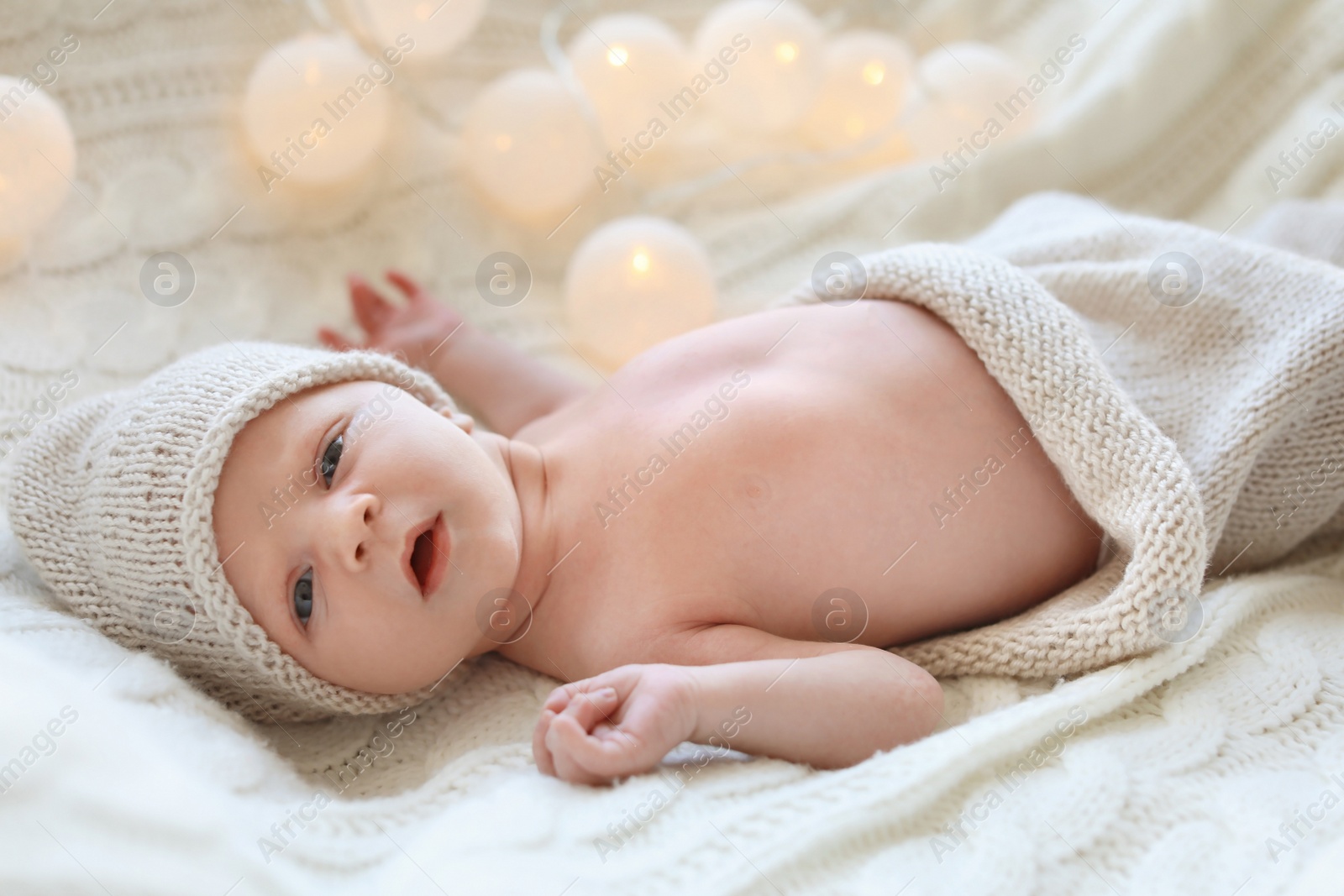 Photo of Adorable newborn baby in hat lying on bed