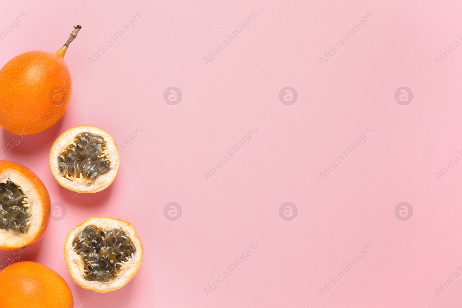 Photo of Delicious ripe granadillas on pink background, flat lay. Space for text