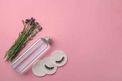 Photo of Bottle of makeup remover, cotton pads, false eyelashes and lavender on pink background, flat lay. Space for text