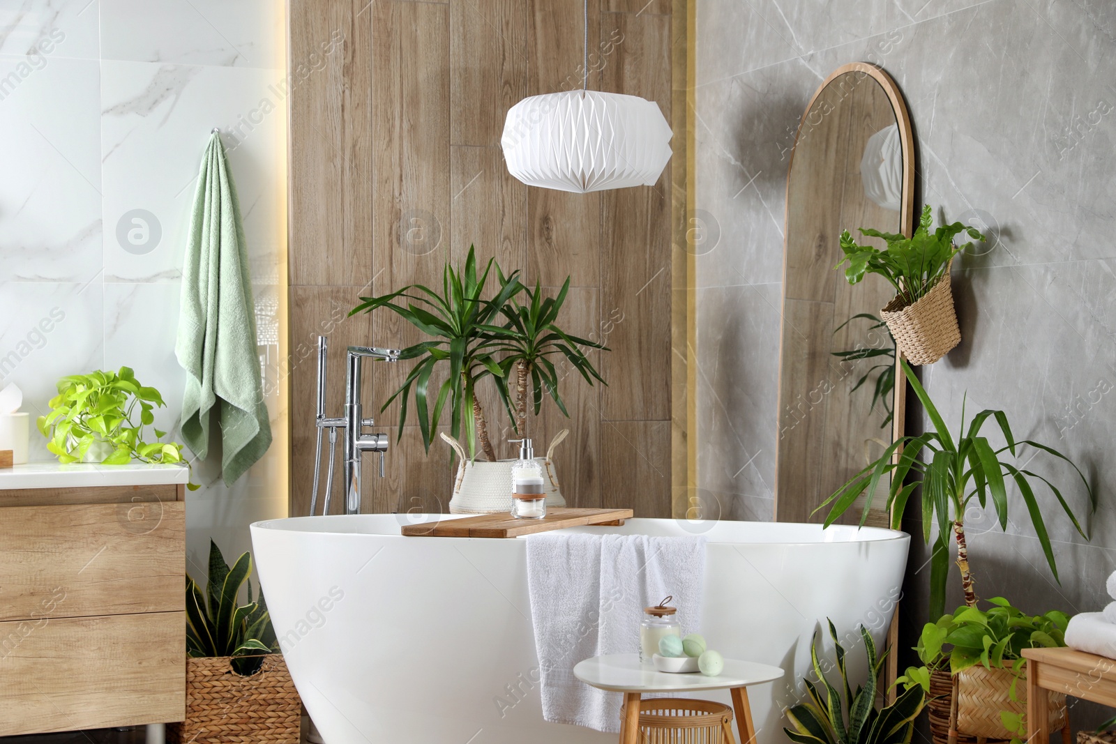 Photo of Modern white tub and beautiful green houseplants in bathroom. Interior design