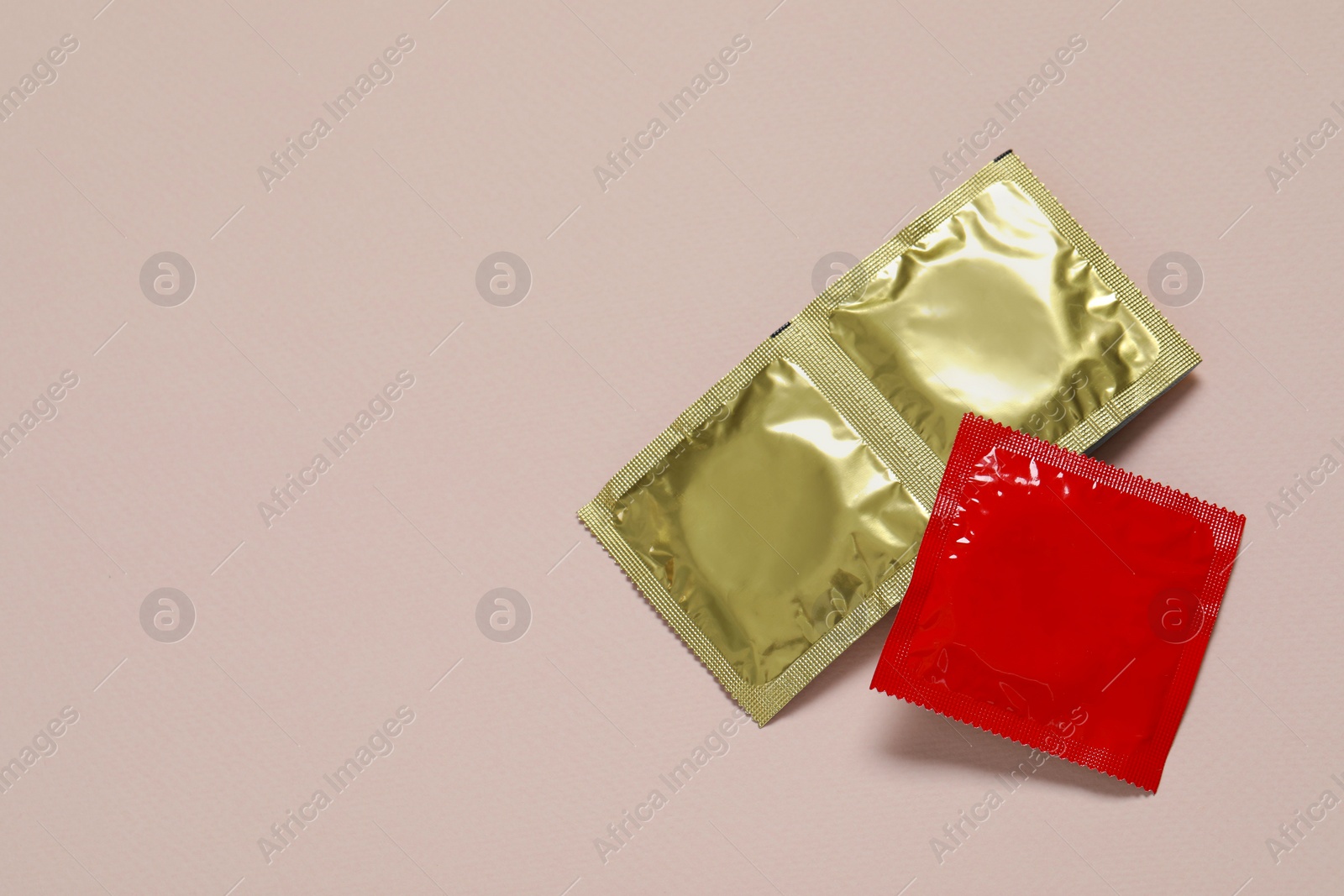 Photo of Condom packages on light pink background, flat lay and space for text. Safe sex