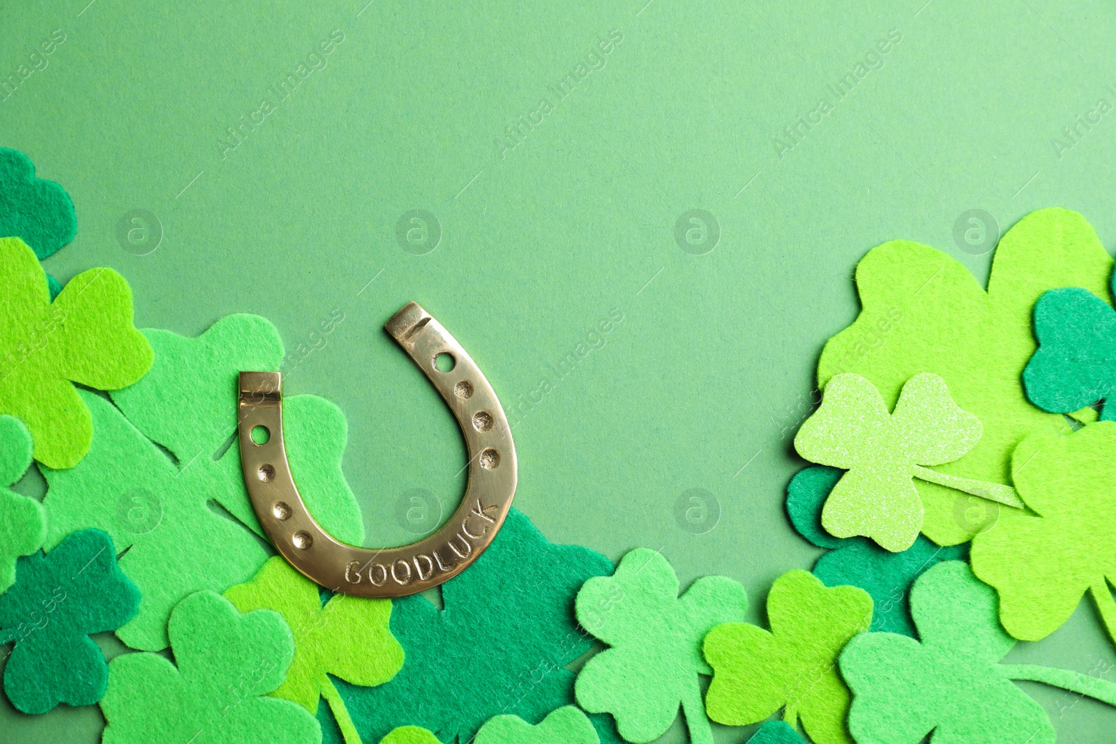 Photo of Flat lay composition with clover leaves and horseshoe on green background. St. Patrick's day