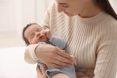 Photo of Mother with her sleeping newborn baby on light background, closeup