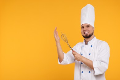 Happy professional confectioner in uniform holding whisk and spatula on yellow background. Space for text