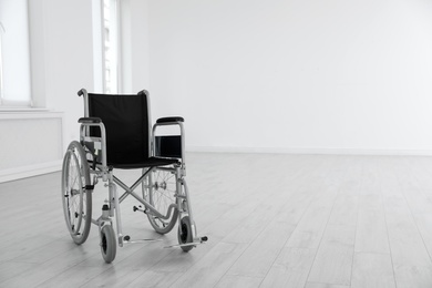 Modern wheelchair in empty room, space for text. Medical equipment