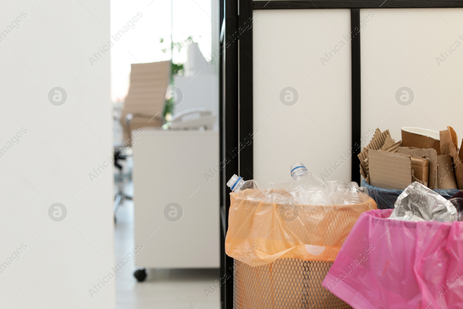 Photo of Full trash cans in modern office, space for text. Waste recycling