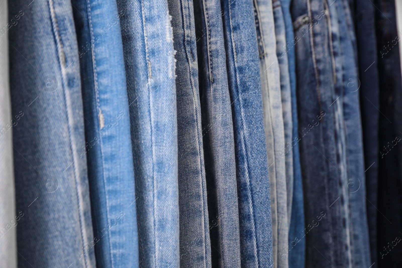 Photo of Different stylish jeans as background, closeup view