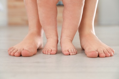 Photo of Mother and her baby standing on floor, closeup of legs