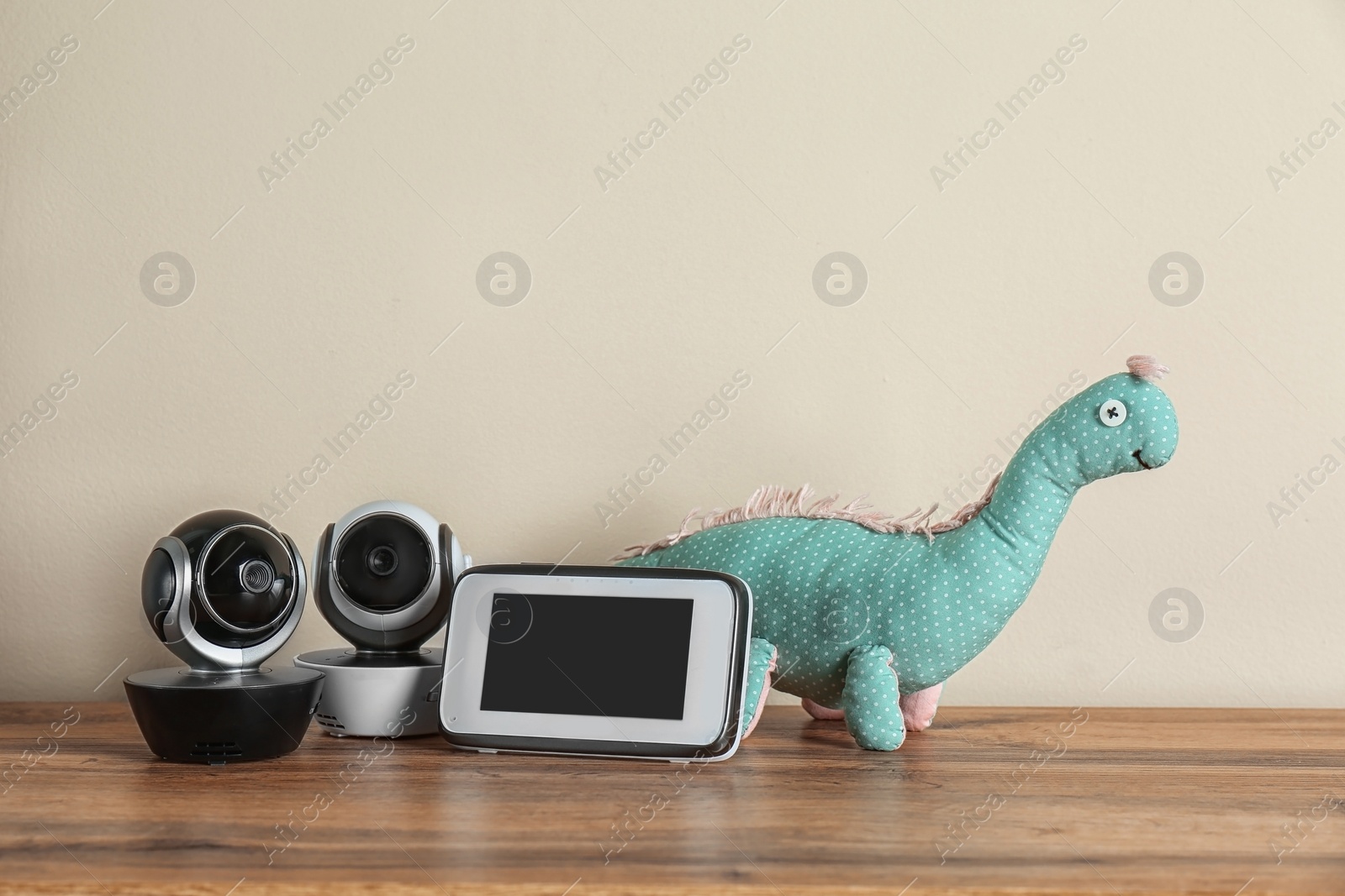 Photo of Baby monitors and toy on wooden table. CCTV equipment