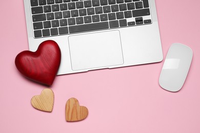 Photo of Laptop, computer mouse and decorative hearts on pink background symbolizing connection in long-distance relationship, flat lay