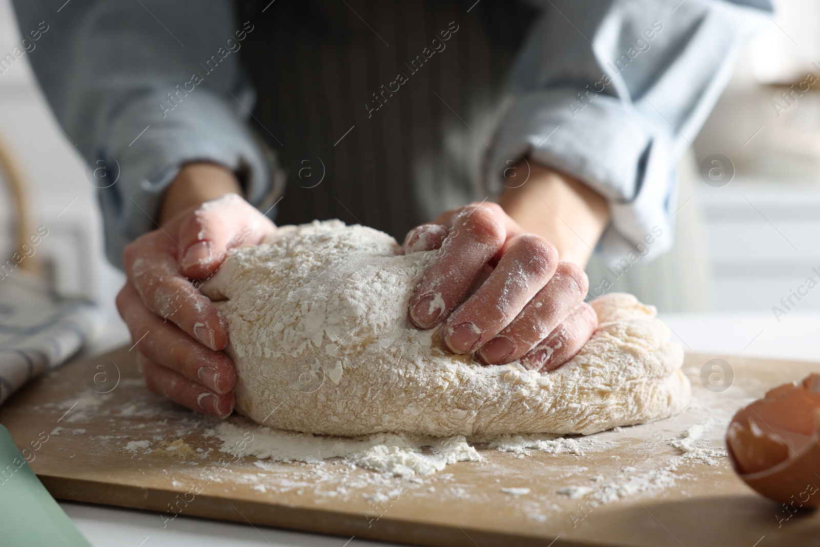 Photo of Woman kneading dough at white wooden table in kitchen, closeup