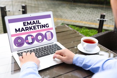 Email marketing. Man using laptop at table outdoors, closeup