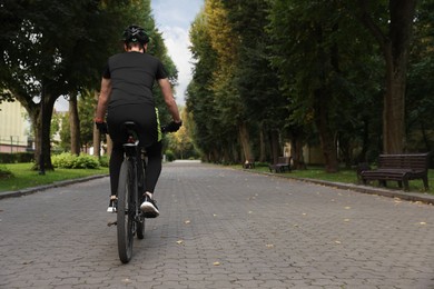 Photo of Man riding bicycle on road outdoors, back view. Space for text