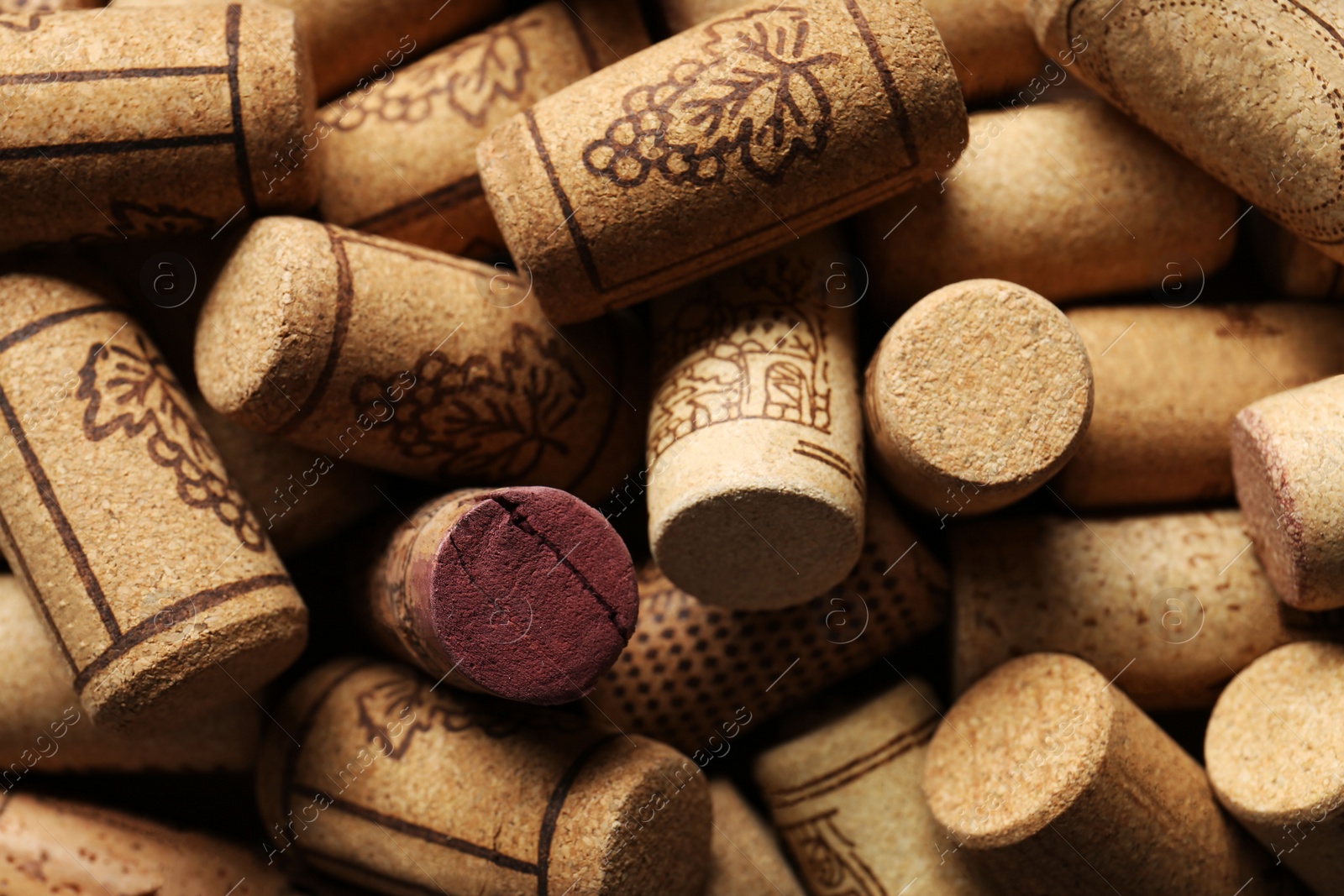 Photo of Many corks of wine bottles with grape images as background, closeup