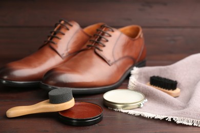Photo of Shoe care products and footwear on wooden table, closeup