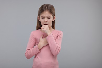 Photo of Sick girl coughing on gray background, space for text